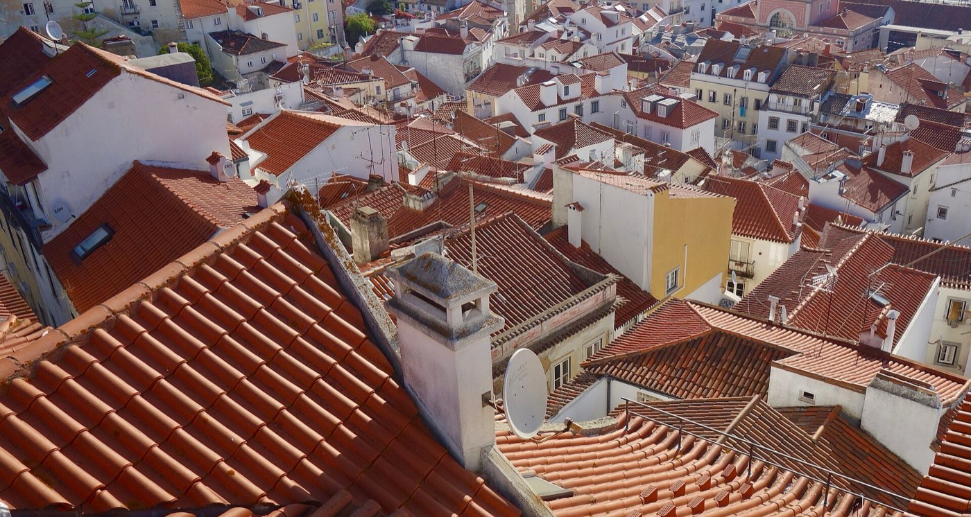 Alfama's terracotta rooftops sloping down to the River Tagus, seen from Miradouro das Portas do Sol