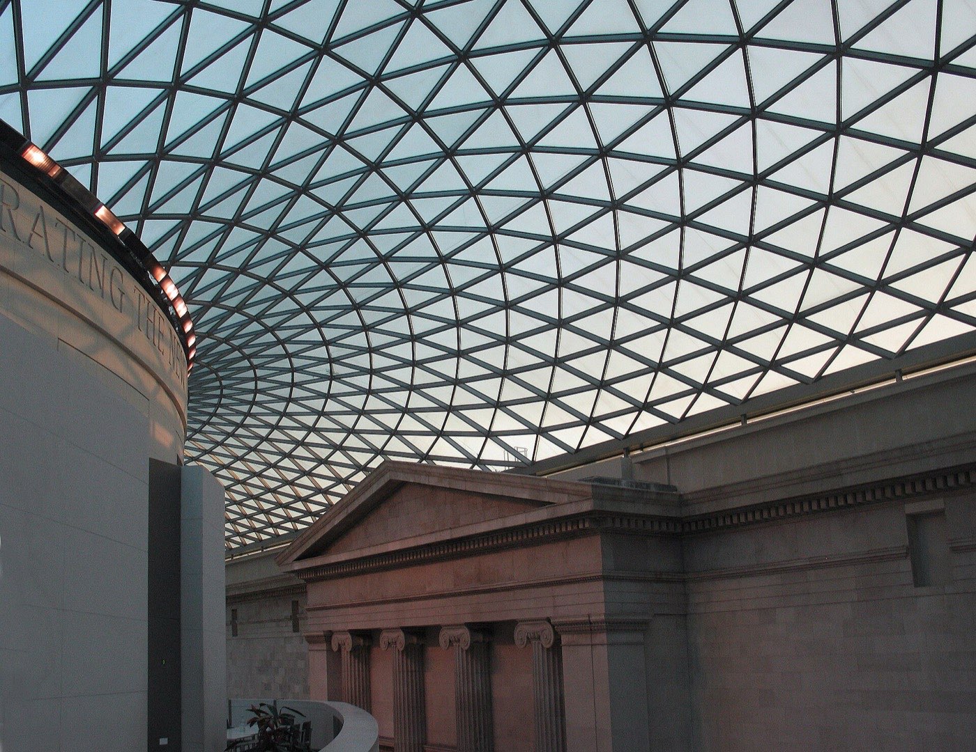 The triangulated glass and steel roof of the British Museum's Great Court curving above the old Reading Room and a classical portico