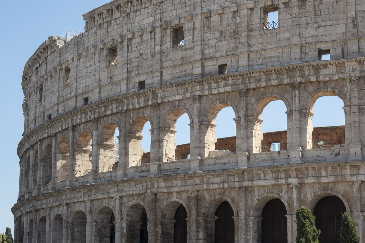 Close-up view of the Colosseum's arched stone facade in Rome under clear blue sky