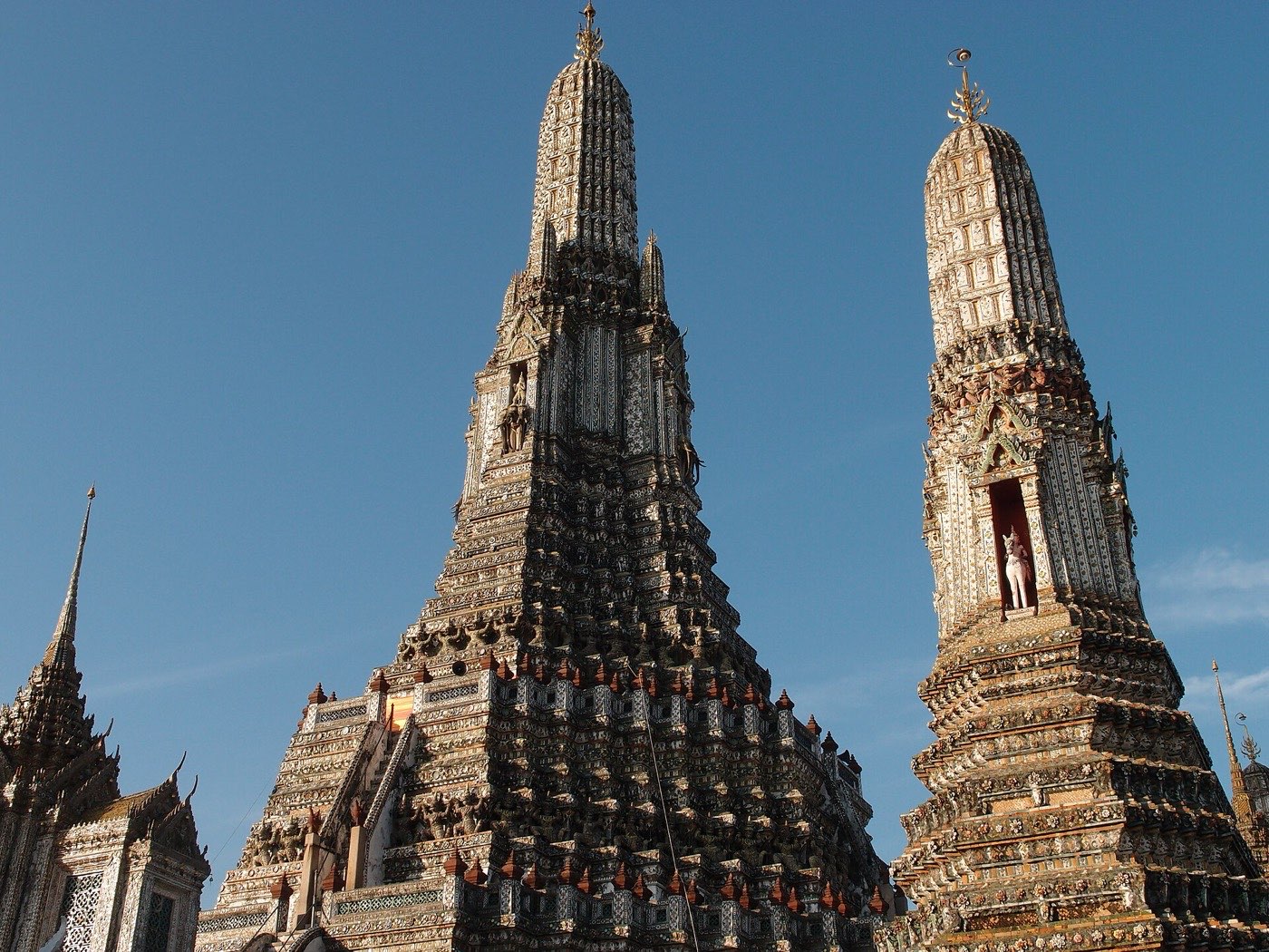 The porcelain-encrusted central prang of Wat Arun rising against a clear blue sky