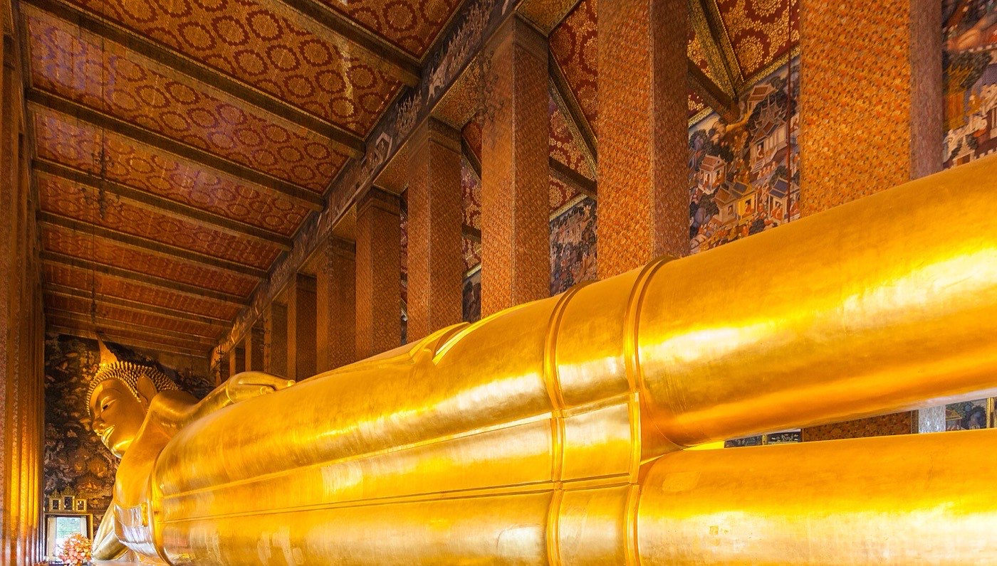 The gold-leafed reclining Buddha at Wat Pho stretching the length of its pillared hall