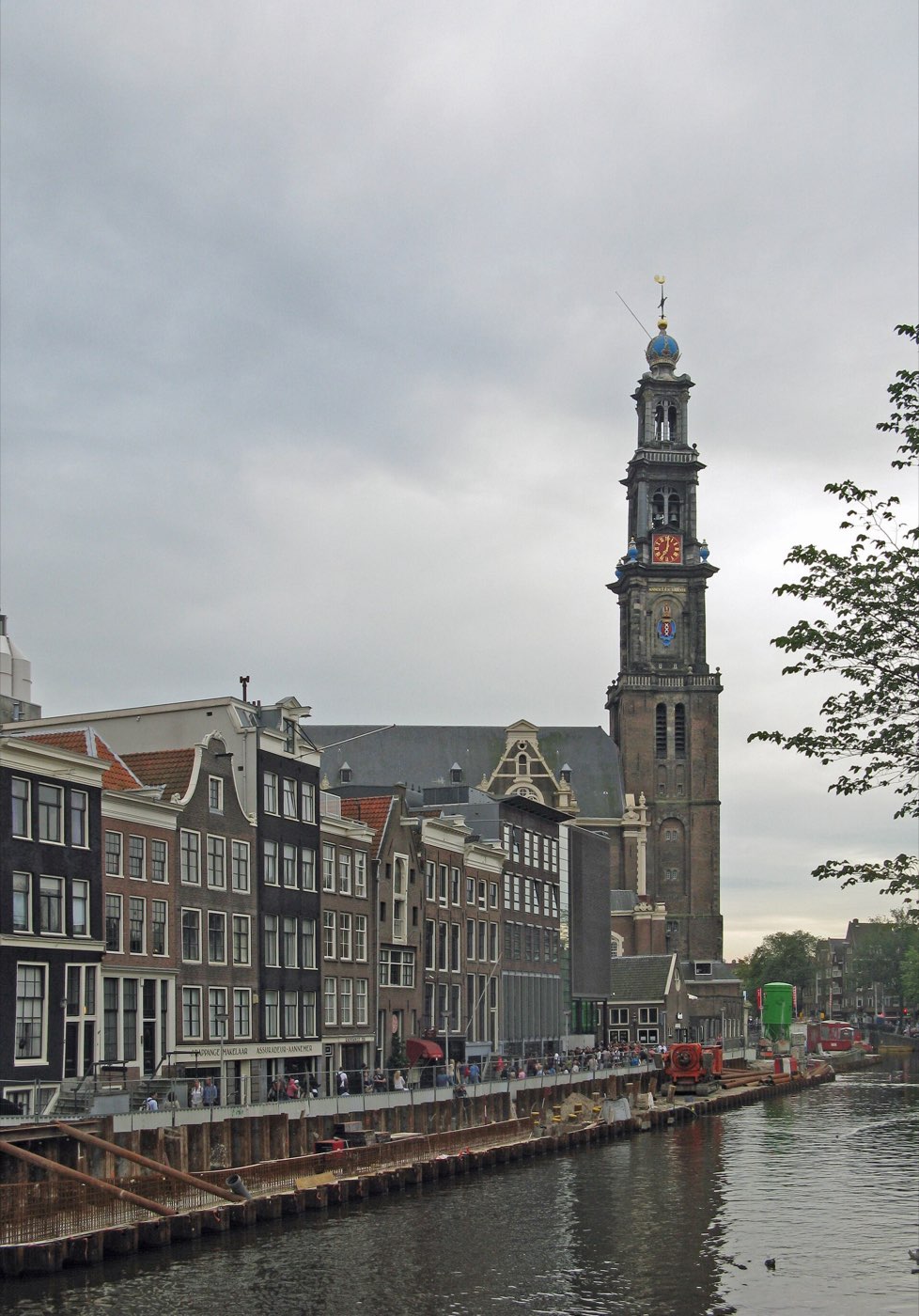 The tall brick tower of the Westerkerk rising above canal houses along Prinsengracht in Amsterdam, with the canal in the foreground