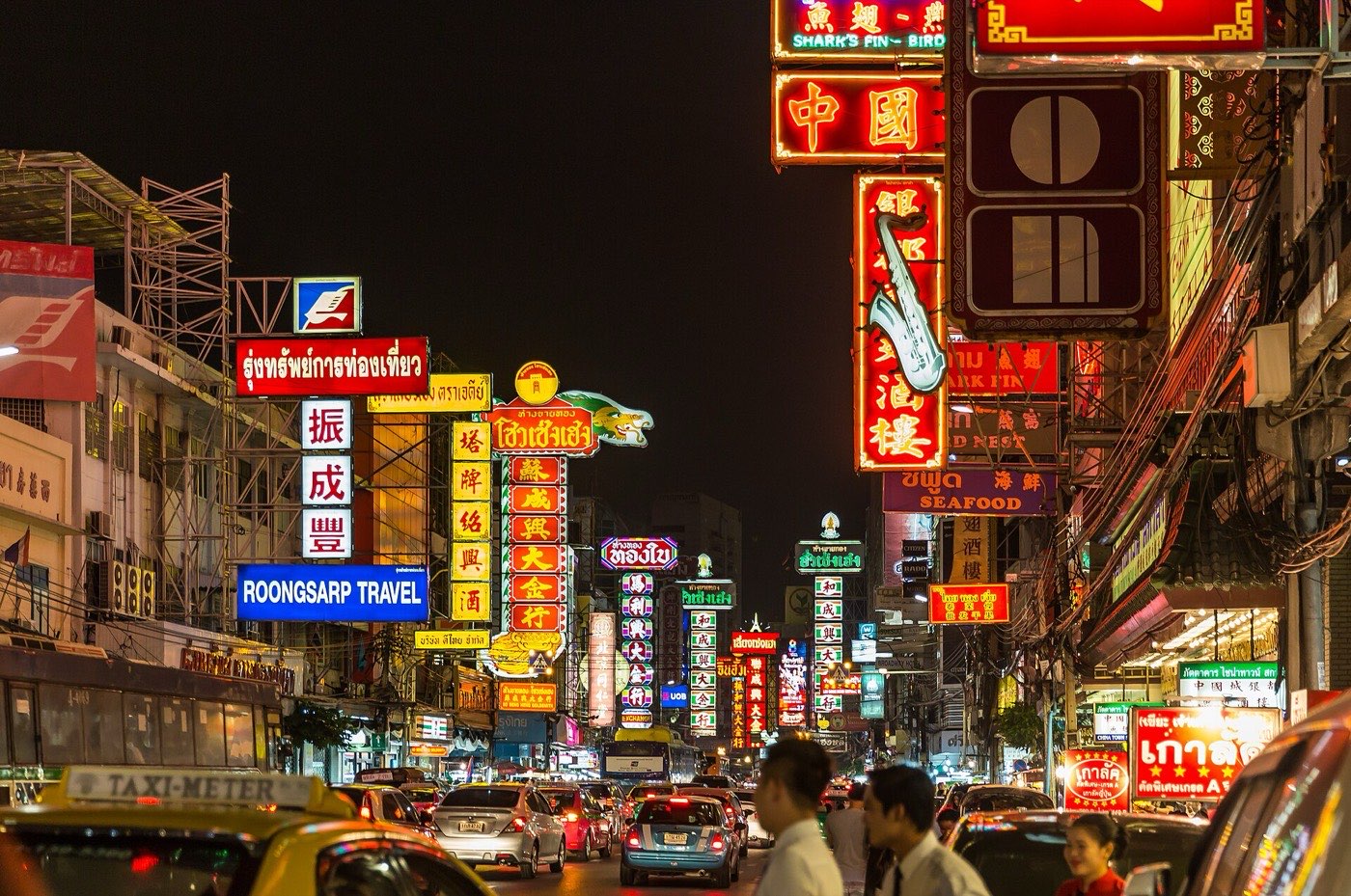 Neon signs in Thai and Chinese crowding above traffic on Yaowarat Road in Bangkok's Chinatown at night